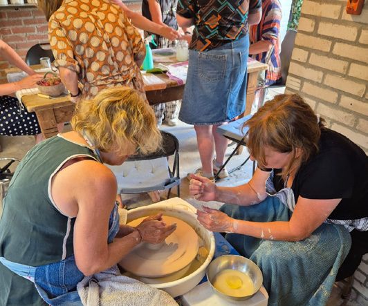 Deelnemers werken samen aan tafel in Atelier Aardwerk